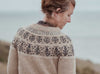 Woman wearing a patterned sweater with a blurred natural background