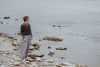 Person standing on rocky shoreline by a body of water