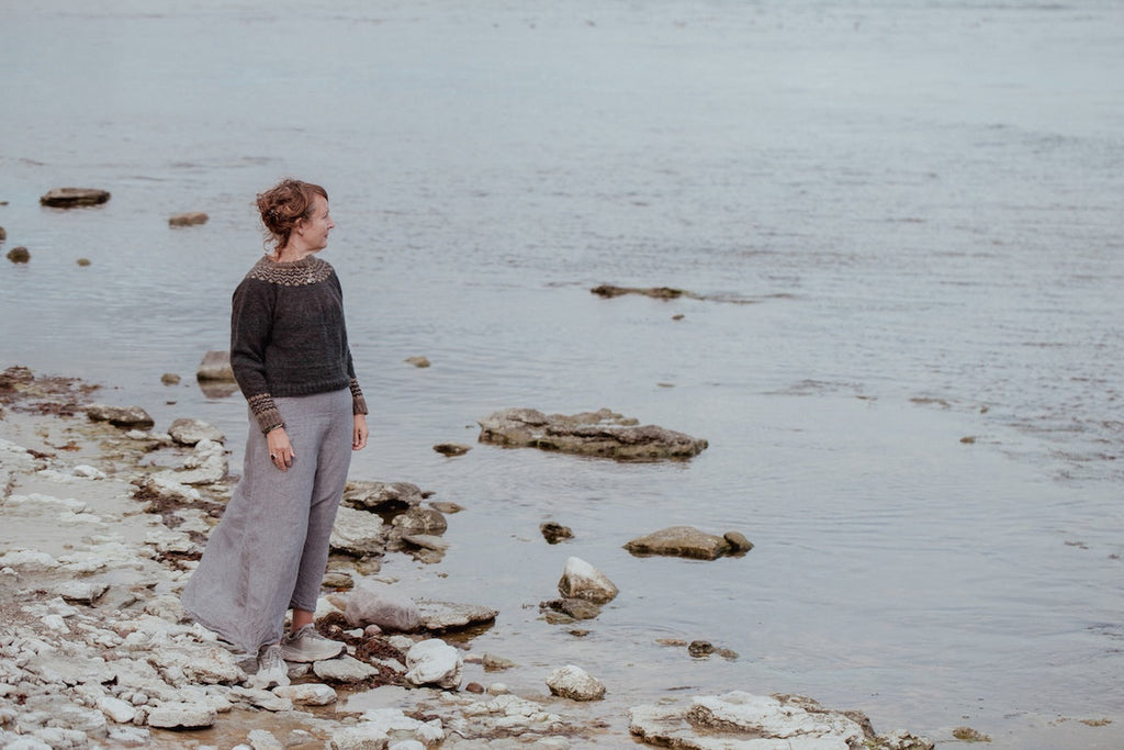Person standing on rocky shoreline by a body of water