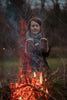 Person wearing mittens by a campfire in a natural setting