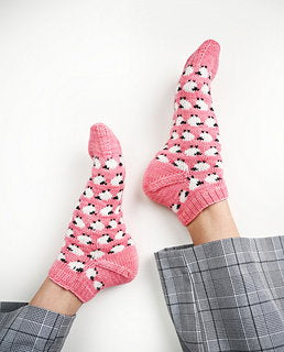 Pink socks with black patterns worn by a person on a white background