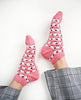 Pink socks with black patterns worn by a person on a white background