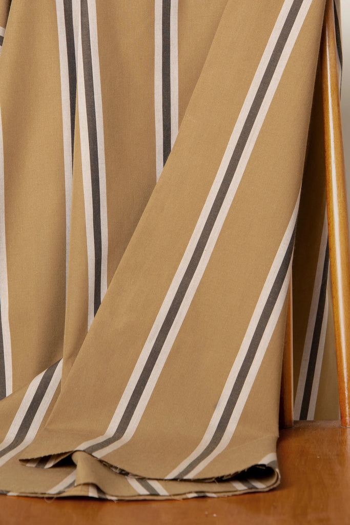 Close-up of striped fabric with brown, beige, and white colors on a wooden surface.