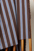 Close-up of a chair with striped fabric and wooden legs.