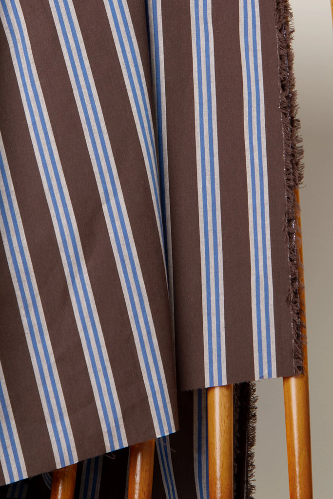 Close-up of a chair with striped fabric and wooden legs.