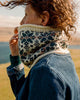 Person wearing a patterned knitted scarf in a scenic outdoor setting