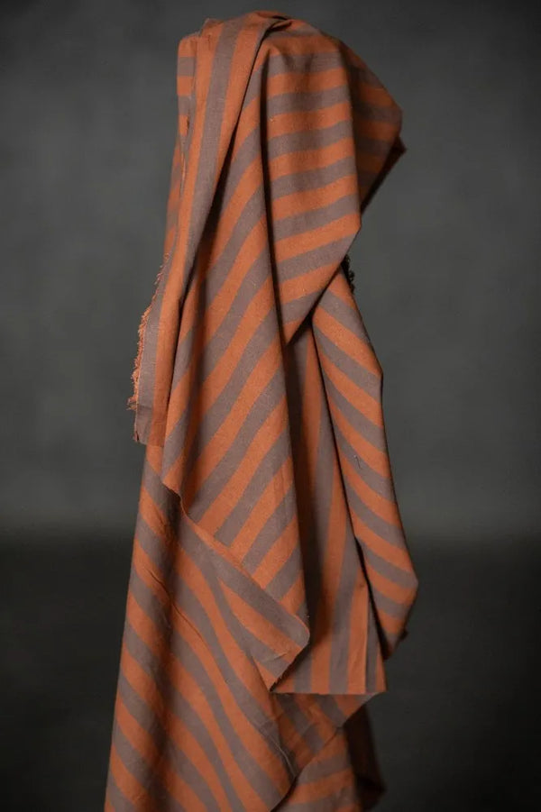 Striped fabric with orange and gray pattern draped over a dark background