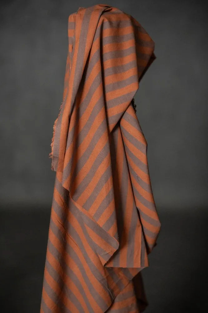 Striped fabric with orange and gray pattern draped over a dark background