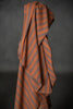 Striped fabric with orange and gray pattern draped over a dark background