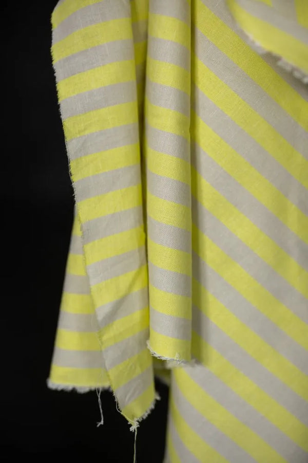 Close-up of yellow and white striped fabric with frayed edges on a black background