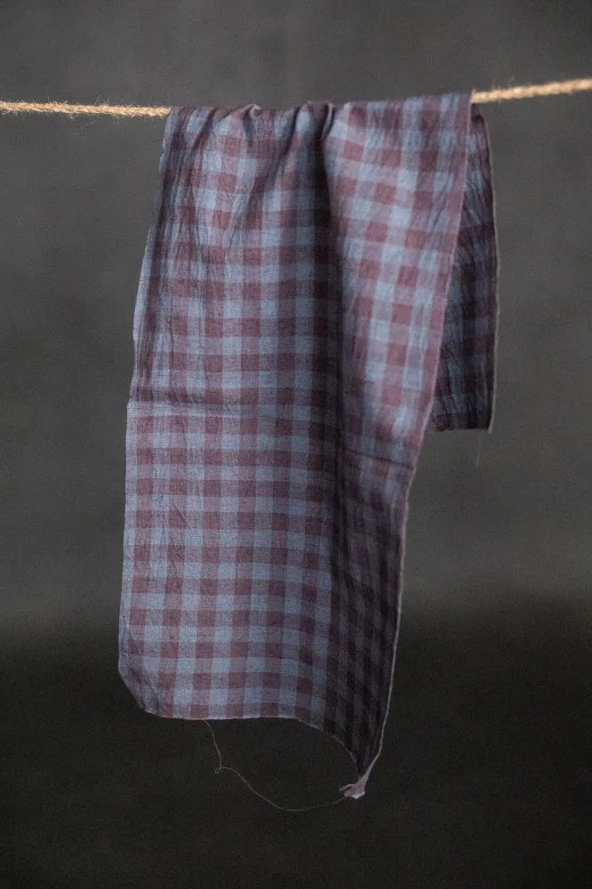 Plaid towel hanging on a rope against a dark background