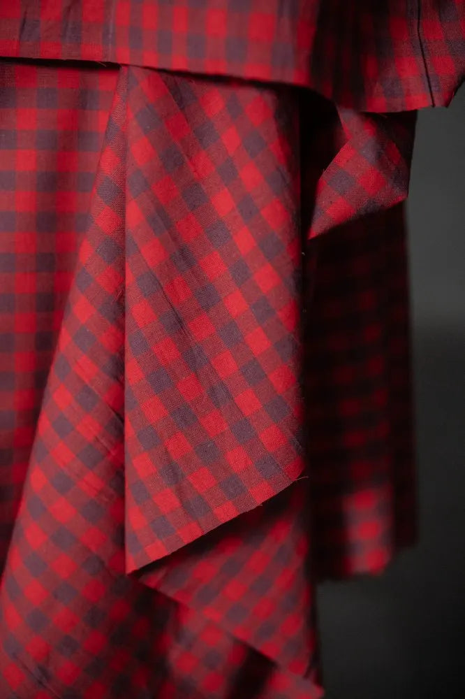 Red and black checkered fabric with a draped effect on a dark background
