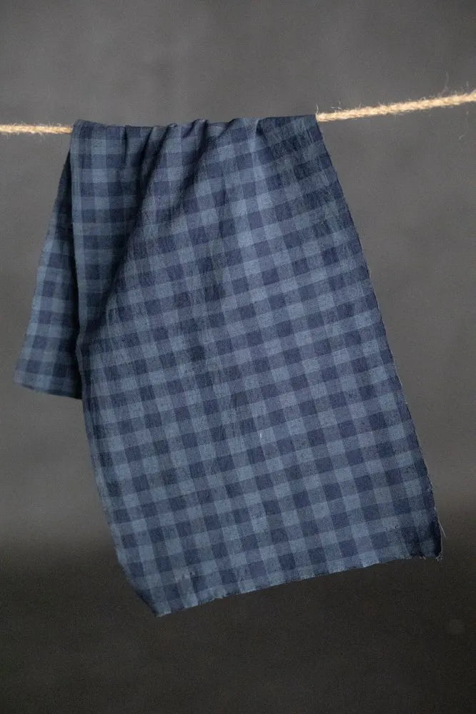Blue checkered towel hanging on a line against a dark background