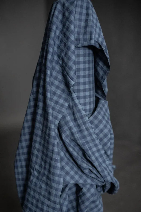 Blue checkered fabric draped over a surface with a dark background