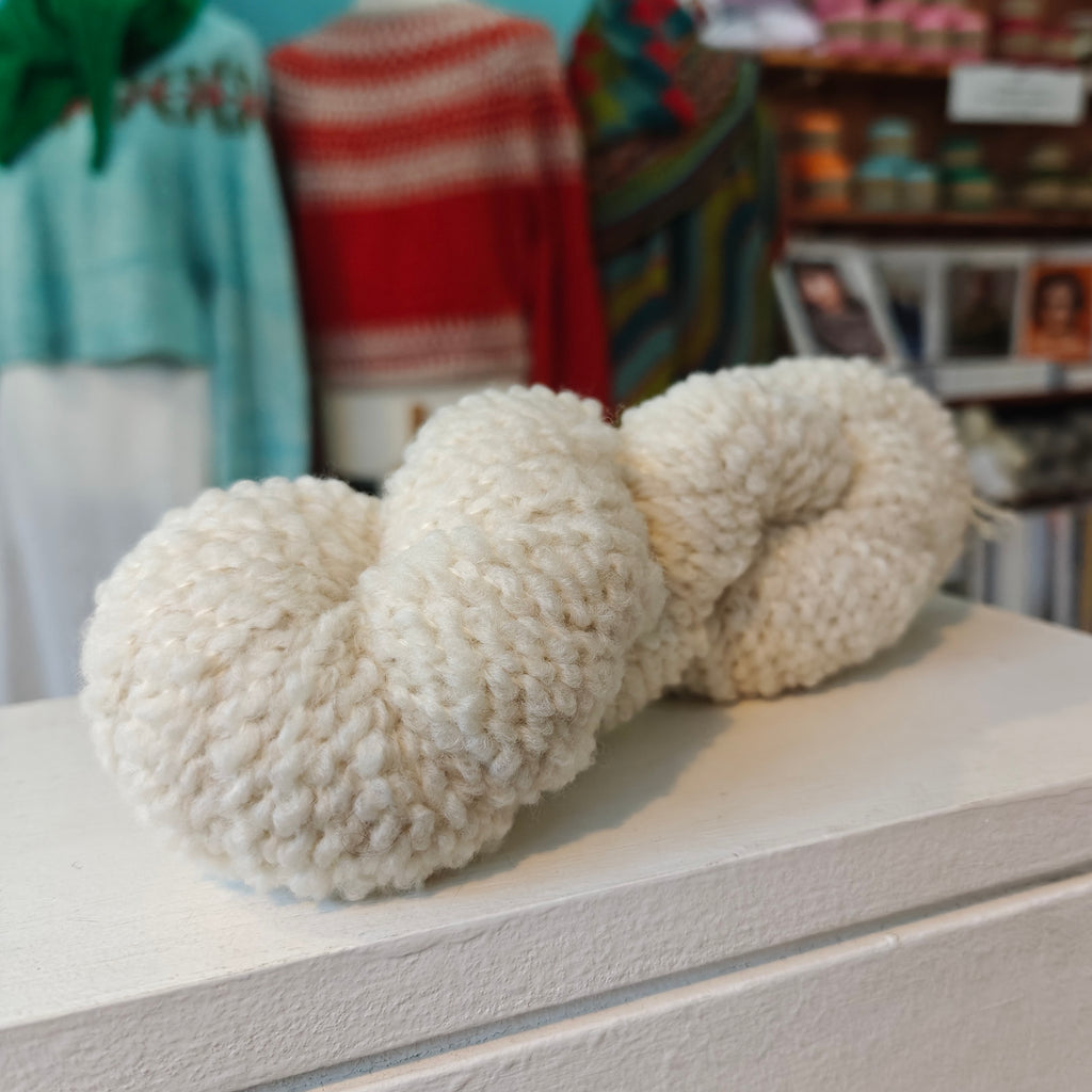 skein of cream wool on a white wooden shelf
