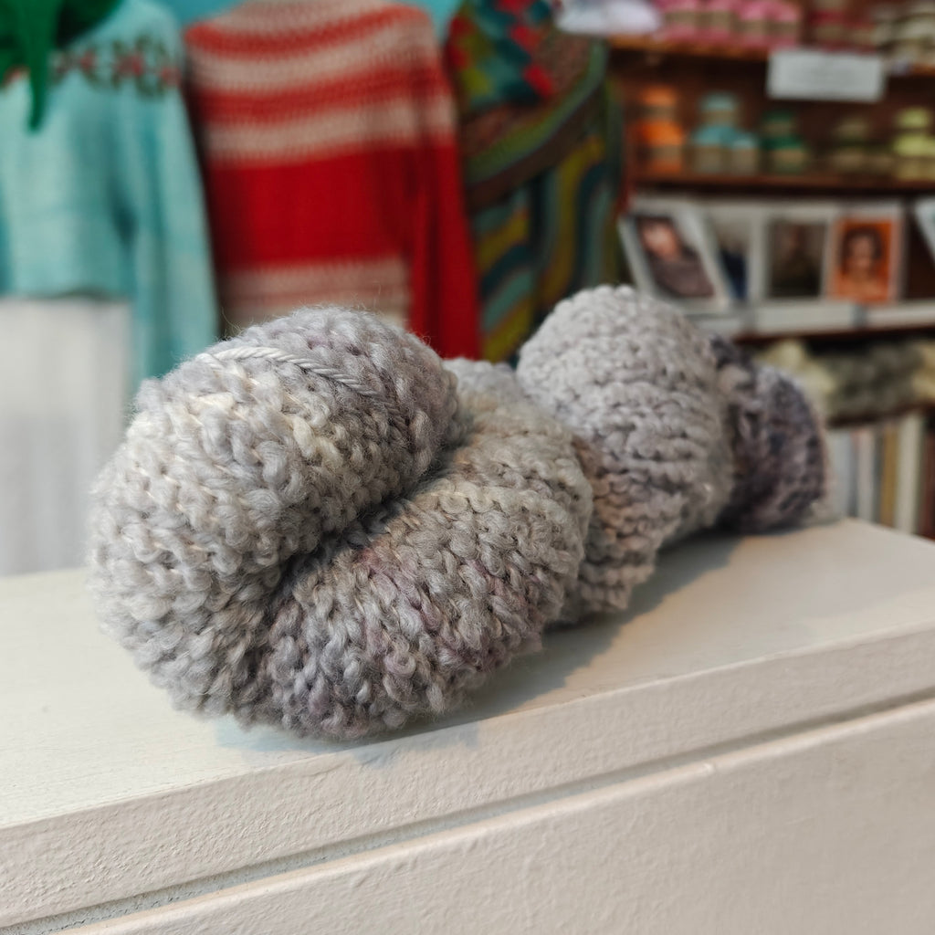 light grey skein of yarn on a white wooden shelf