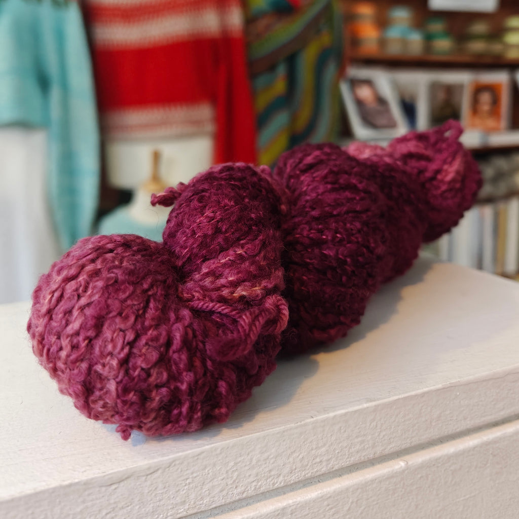skein of burgundy purple wool on wooden shelf