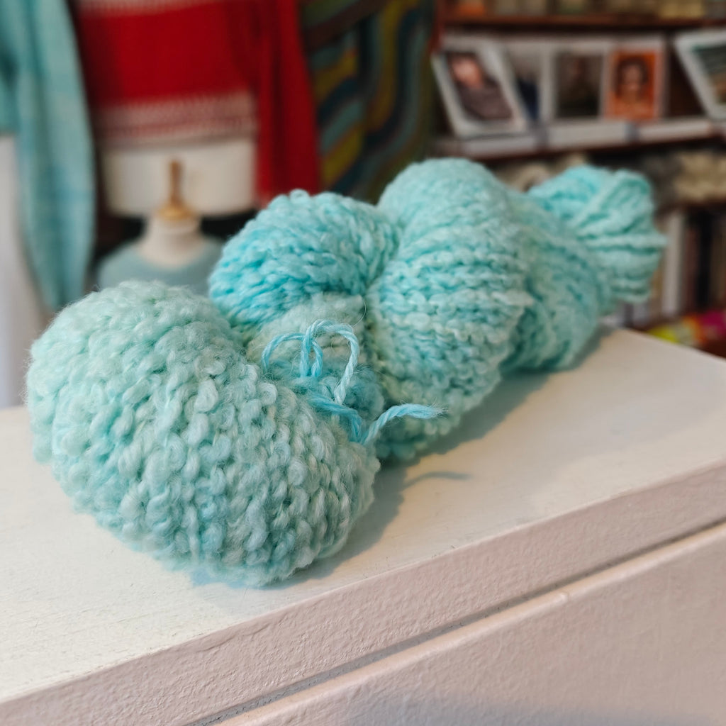 light blue yarn ball on a wooden surface with a blurred background