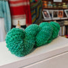 skein of green yarn on a shelf with a blurred background