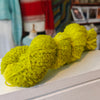skein of bright green yarn on a shelf with a blurred indoor background