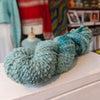 skein of teal yarn on a surface with a blurred background