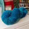 one skeins of blue wool on a surface with a blurred background