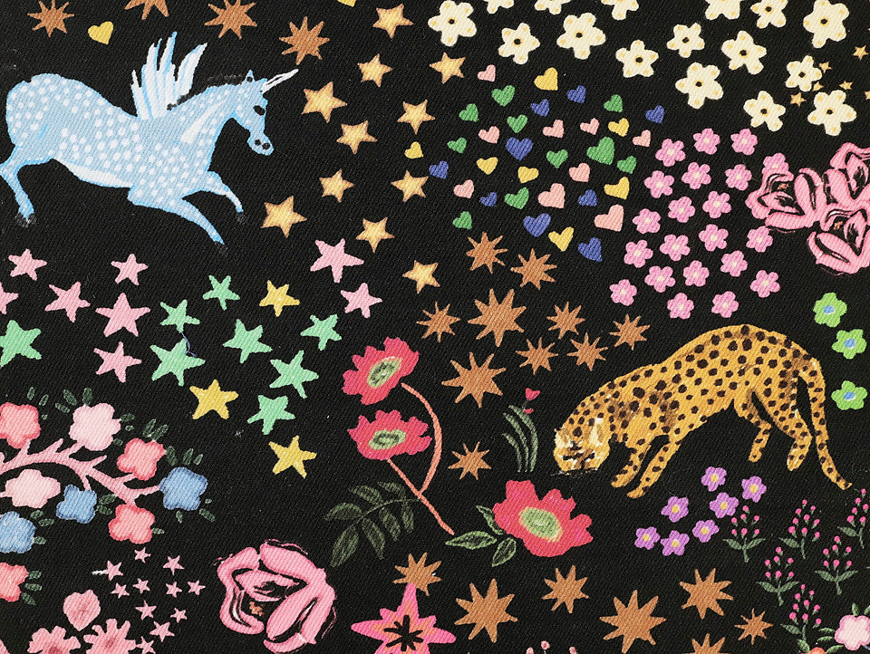 Colorful fabric pattern with unicorns, leopards, and flowers on a black background