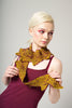 Woman wearing a mustard yellow knitted scarf against a plain background
