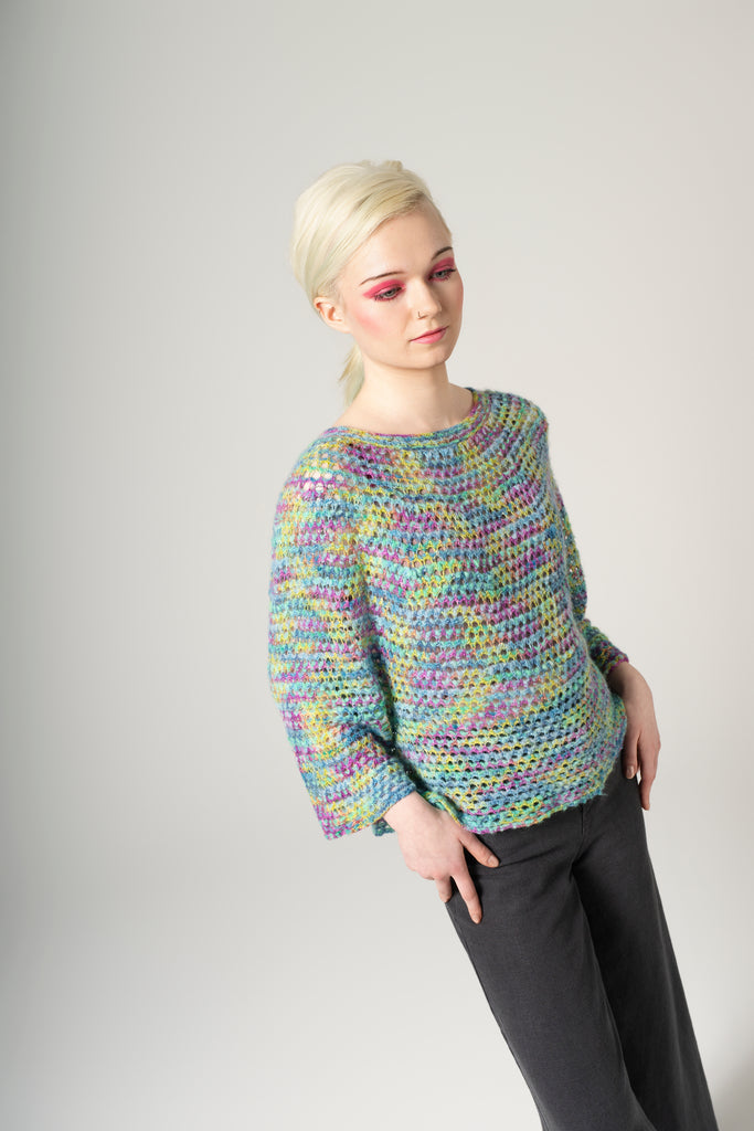 Person wearing a colorful knitted sweater against a plain background