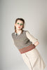 Person wearing a striped sweater vest over a collared shirt on a plain background