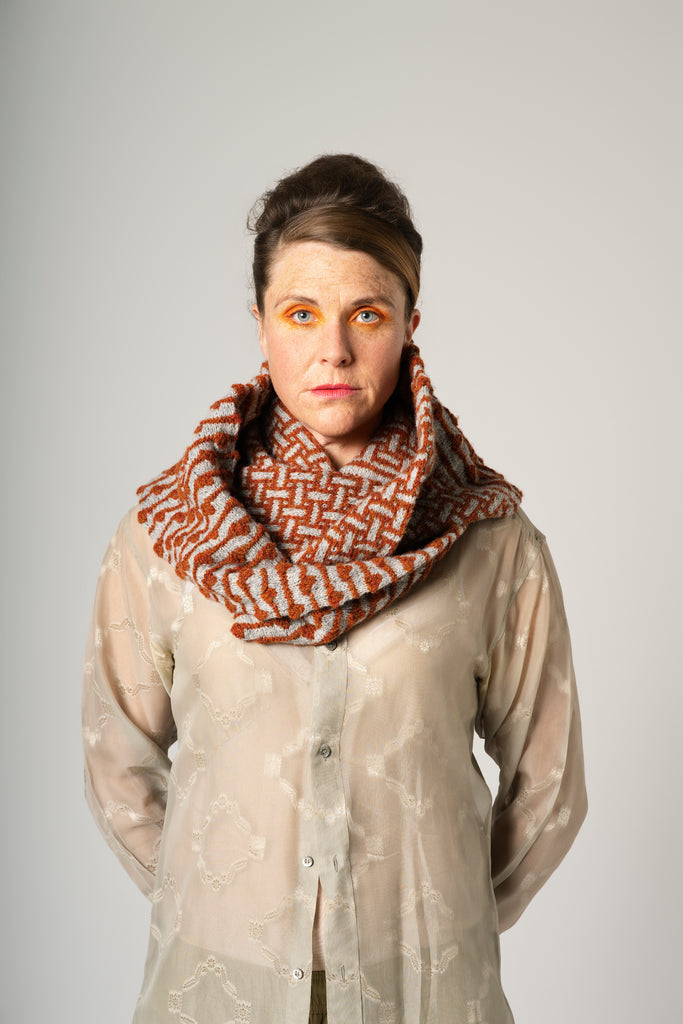 Person wearing a patterned scarf against a plain background