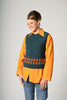 Person wearing an orange shirt over a patterned vest on a plain background