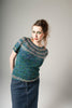 Woman wearing a knitted sweater and jeans against a plain background