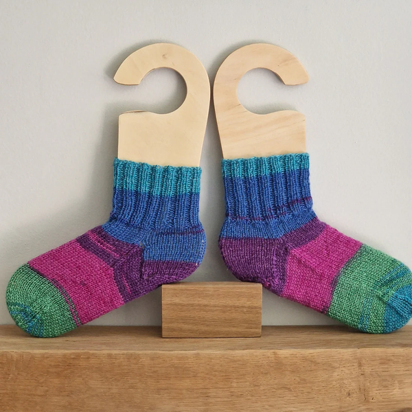 a set of sock blockers covered in a colourful pair of socks