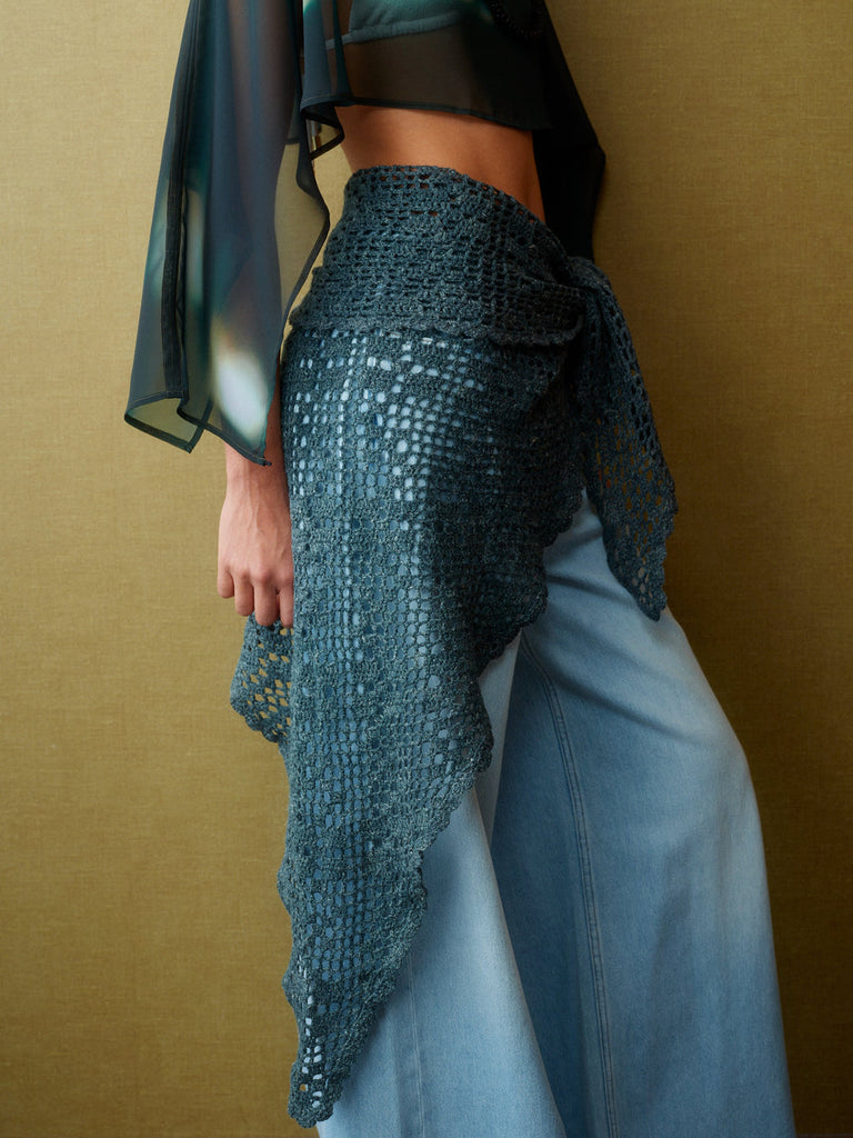 Person wearing a textured blue garment over a plain background