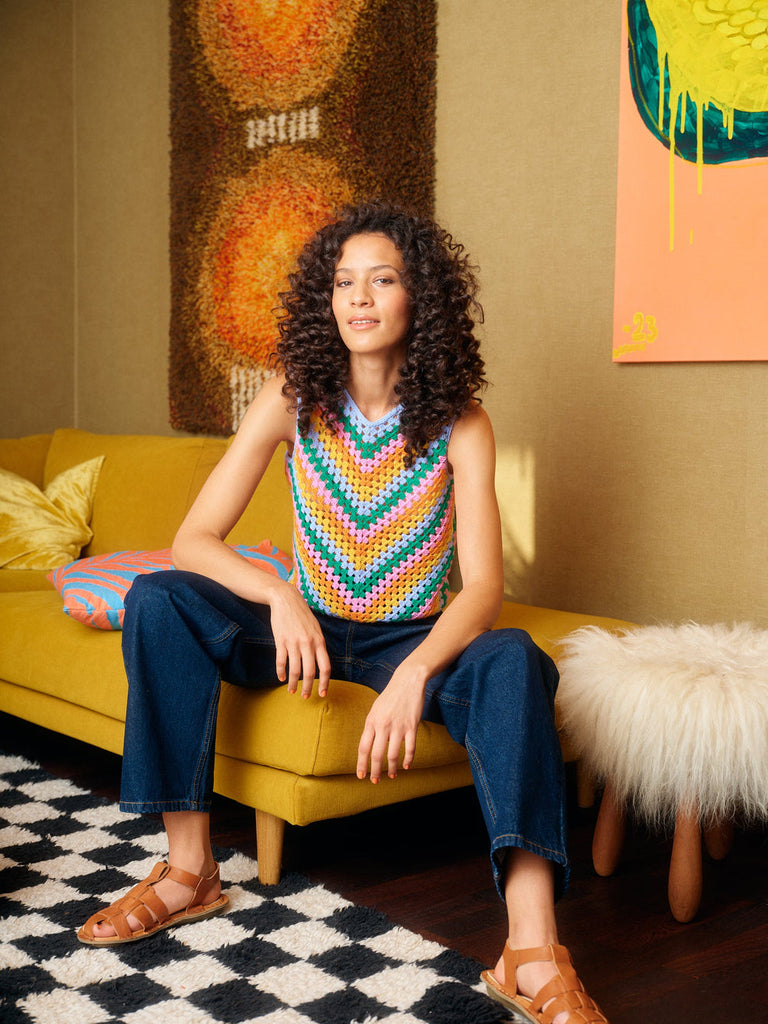 Woman sitting on a yellow couch in a room with colorful artwork on the walls.