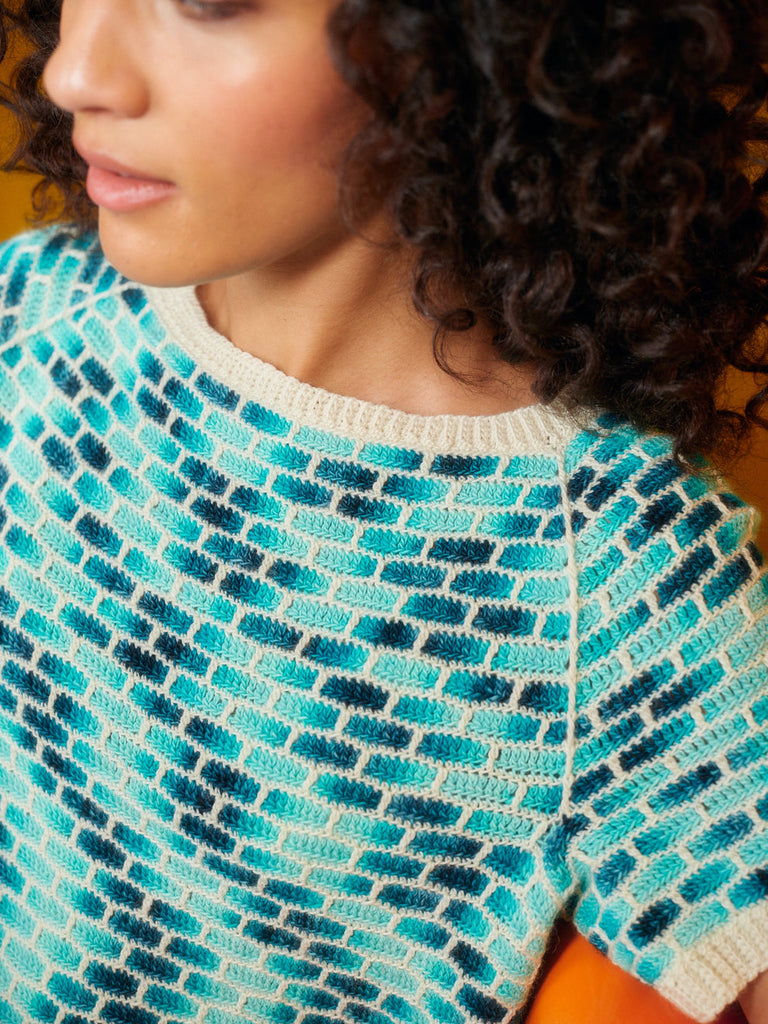 Person wearing a patterned sweater with blue and green colors.
