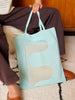 Person holding a light blue mesh tote bag on a patterned rug.
