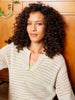 Woman wearing a beige knitted sweater against a wooden background