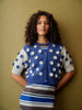 Woman wearing a blue and white patterned cardigan against a beige background
