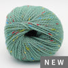 Teal yarn ball with multicolored speckles on a white background